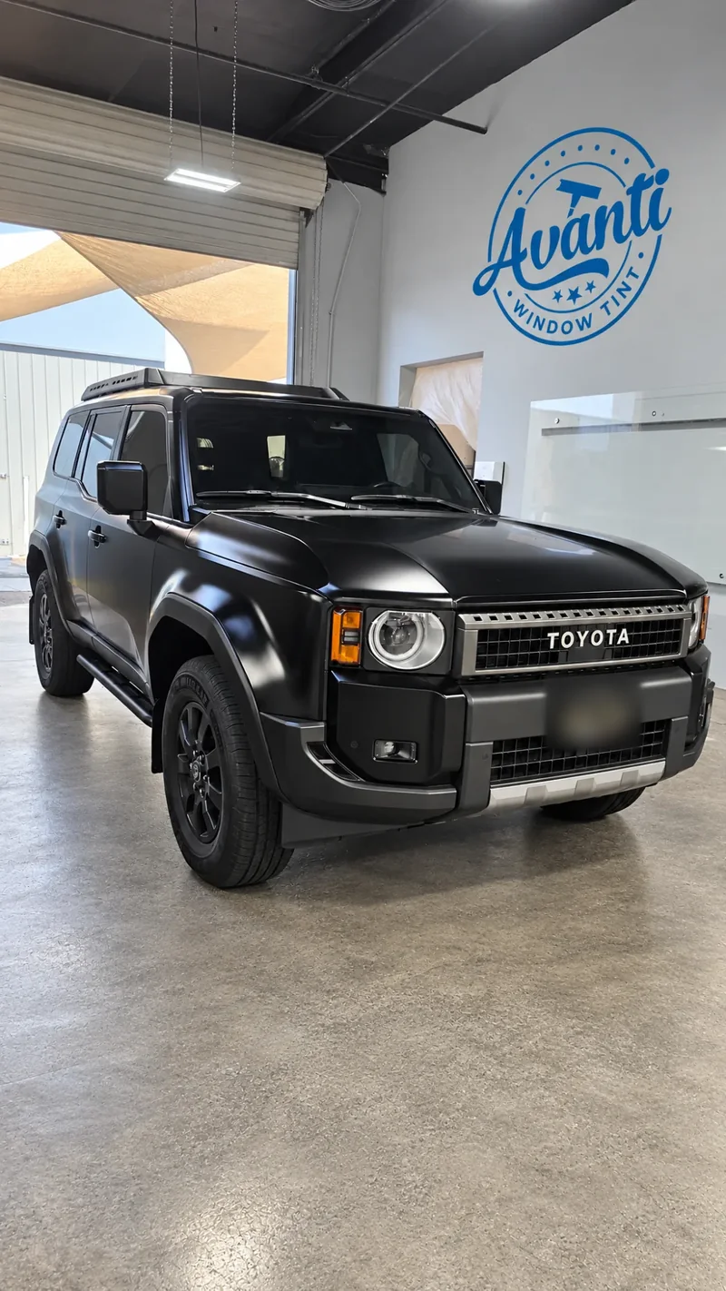 Matte black Toyota Land Cruiser with tinted windows inside the Avanti Window Tint shop